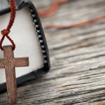 Small cross necklace/rosary on the edge of a Bible